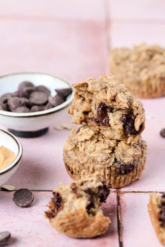 two pb baked oatmeal cups stacked on top of another on pink surface.