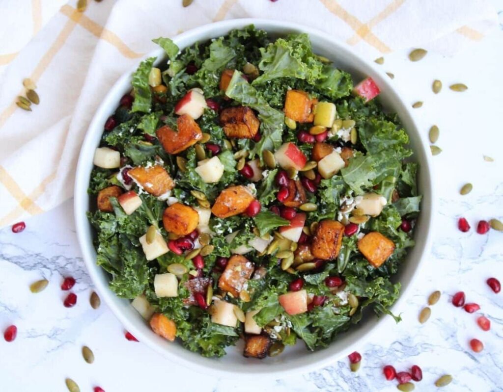 Photo of a fall kale salad with butternut squash, goat cheese, pomegranate seeds, pepitas, and apple