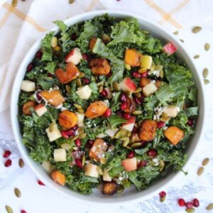 Photo of a fall kale salad with butternut squash, goat cheese, pomegranate seeds, pepitas, and apple