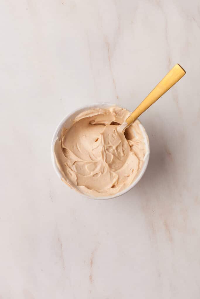 peanut butter yogurt dip in a small bowl with gold spoon.