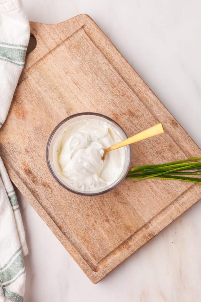 high protein ranch dip in a bowl with gold spoon inserted.