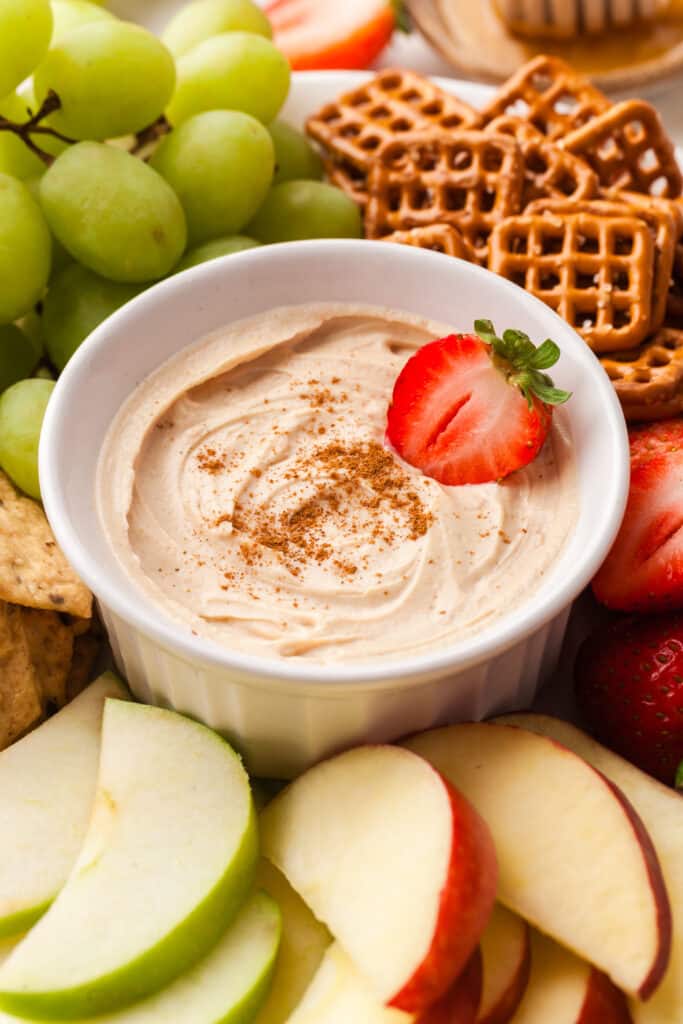 peanut butter yogurt dip with a strawberry dipped in and other dippers surrounding it.
