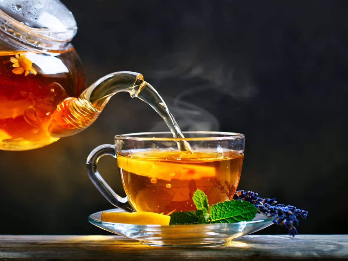 photo of a clear tea pot pouring tea into a clear tea cup