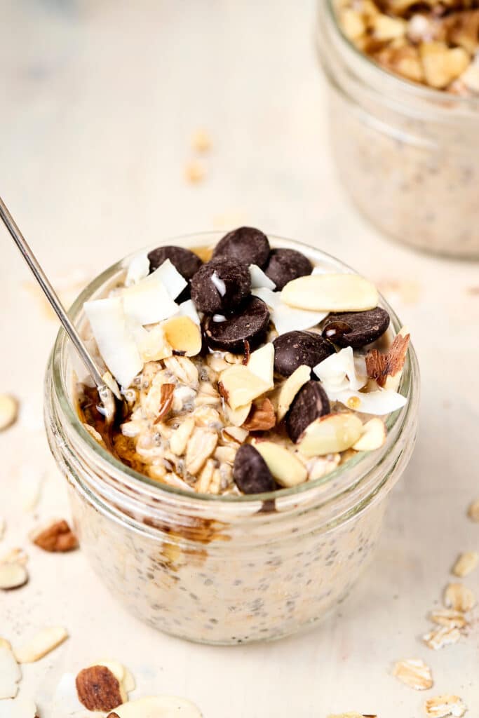 almond joy overnight oats in a small mason jar with spoon.