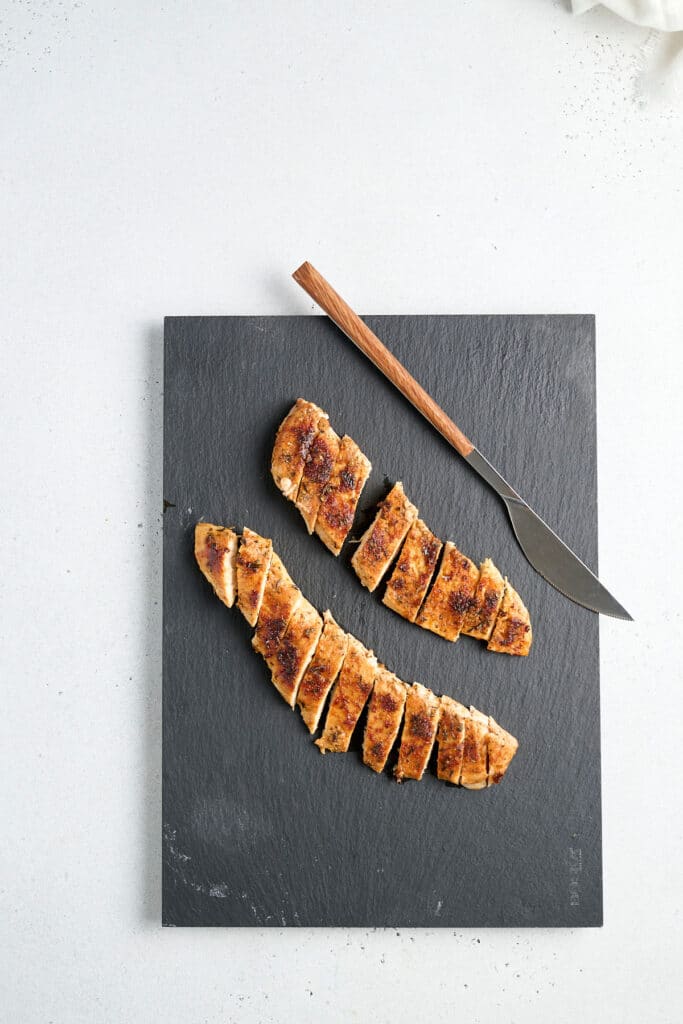 blackened sliced chicken on a charcoal cutting board.
