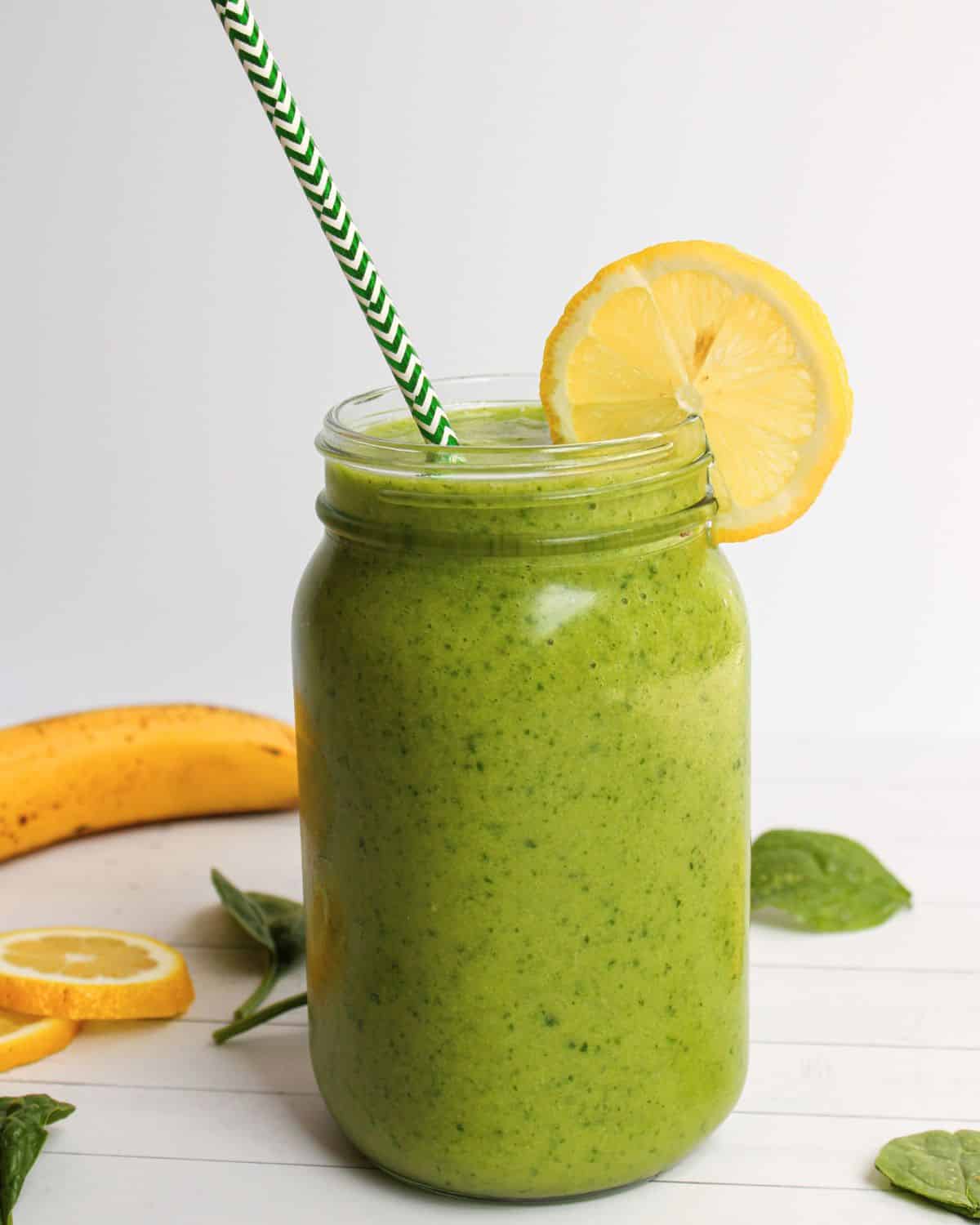 Green smoothie with a lemon wedge on the rim of a mason jar.
