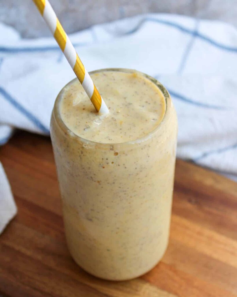 Mango smoothie made with kefir in a glass on a cutting board.