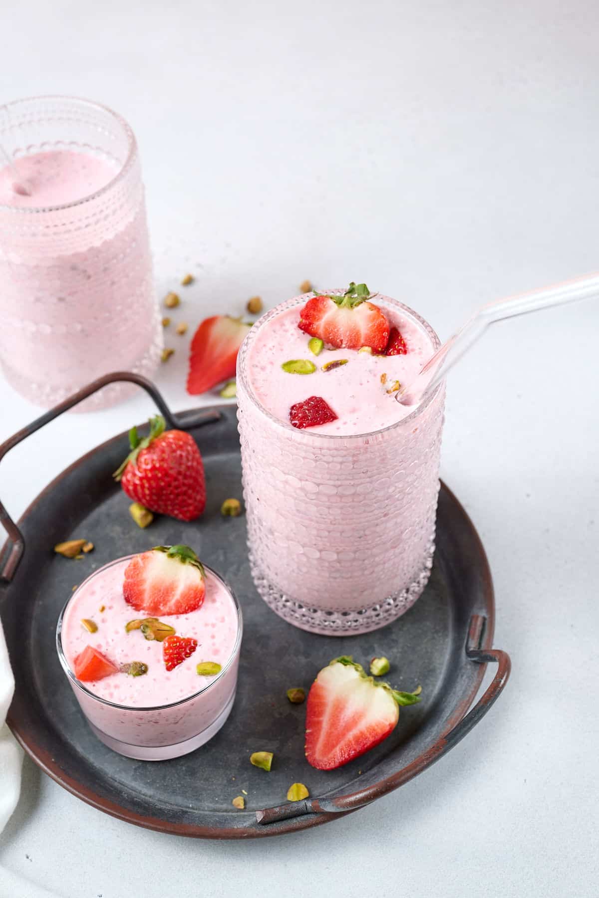 cheese smoothies in different glasses with strawberry garnish.
