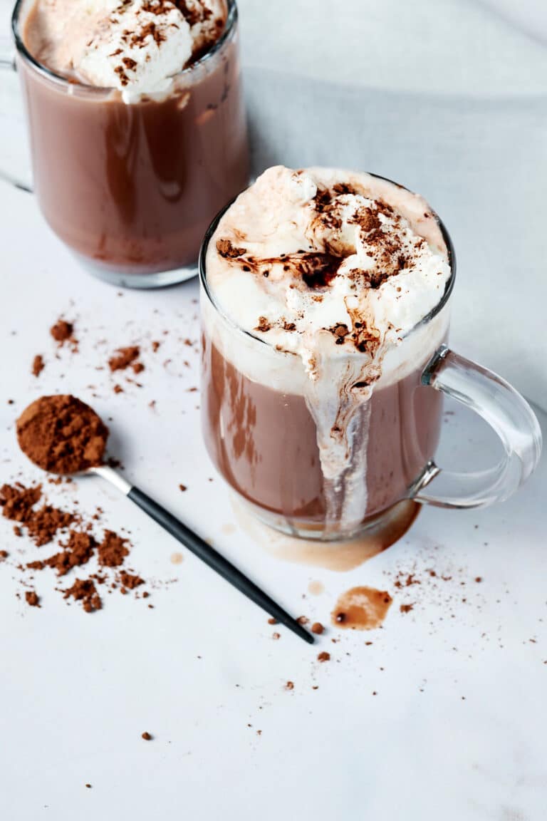 bone broth hot cocoa in a clear glass mug with whipped cream on top.