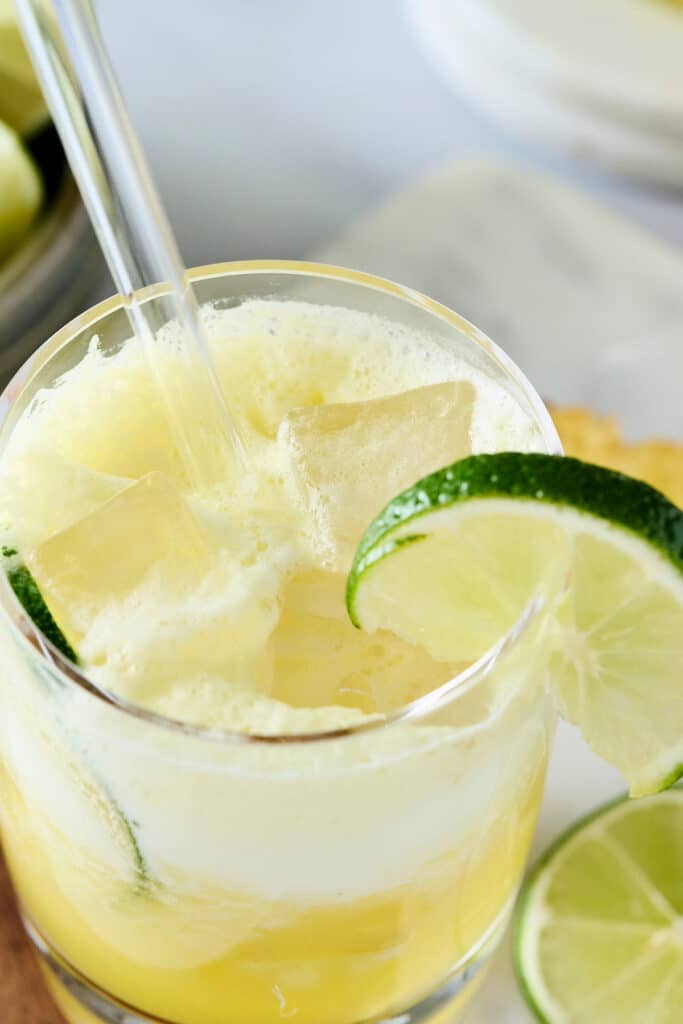 pineapple cortisol mocktail in a glass with lime garnish and glass straw.