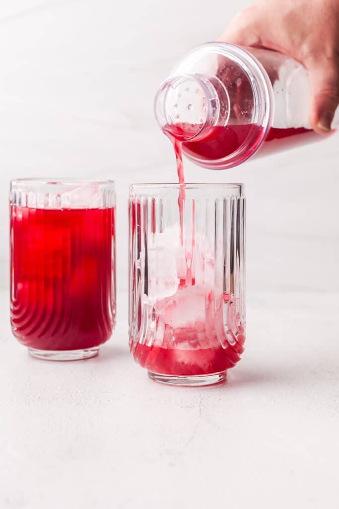 pouring cortisol cocktail into a glass from a drink shaker.