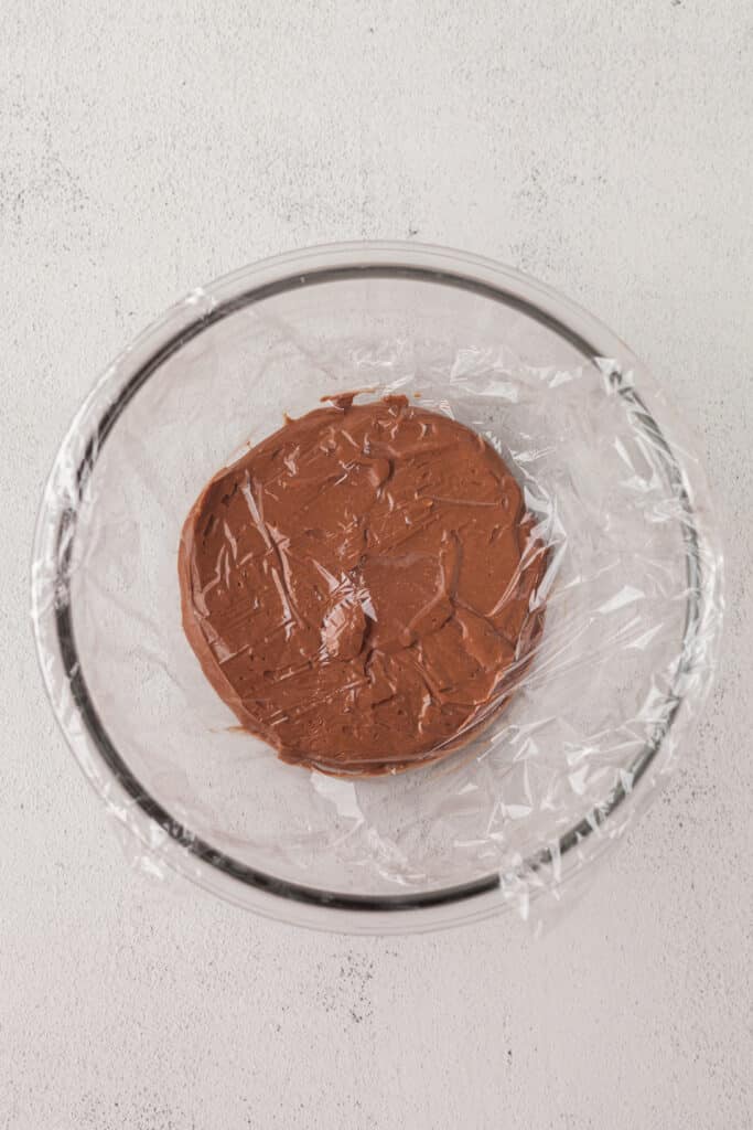 cottage cheese chocolate pudding in a glass bowl with plastic wrap.