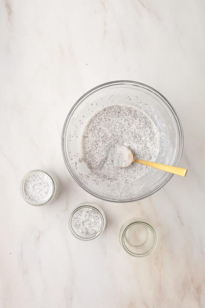 chia pudding in a glass bowl being scooped into smaller jars.