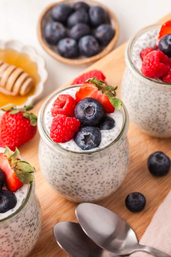 greek yogurt chia seed pudding in glass jars topped with berries.