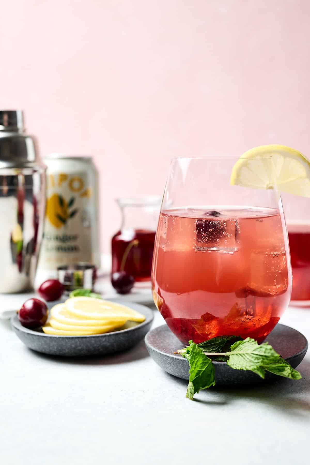 sleepy girl mocktail in a stemless wine glass with lime on the rim; ingredients in the background.