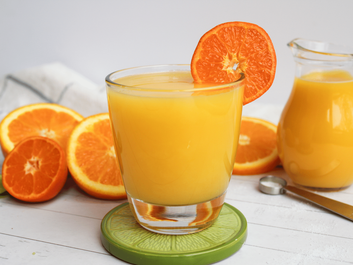 cup of orange juice with some deacorative citrus fruit.