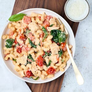 baked feta pasta with chicken on a white plate with fork.