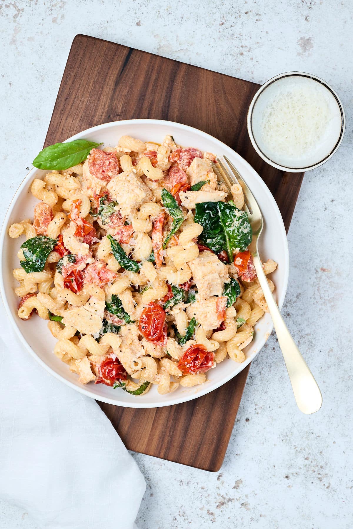 baked feta pasta with chicken on a white plate with fork.