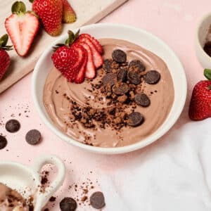 healthy brownie batter dip in a white bowl with strawberries.
