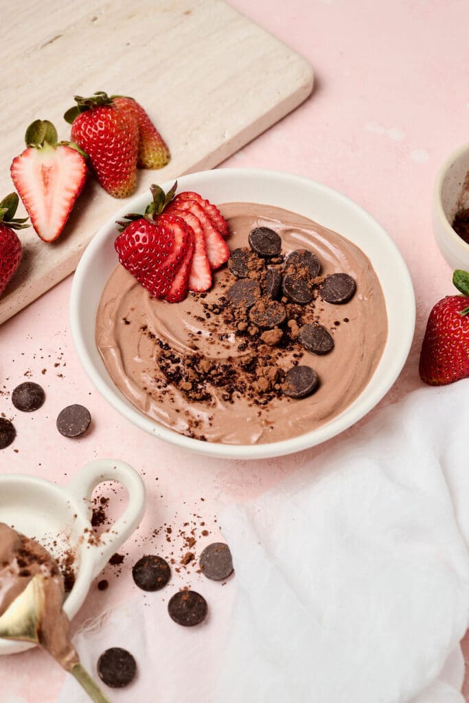 healthy brownie batter dip in a white bowl with strawberries.