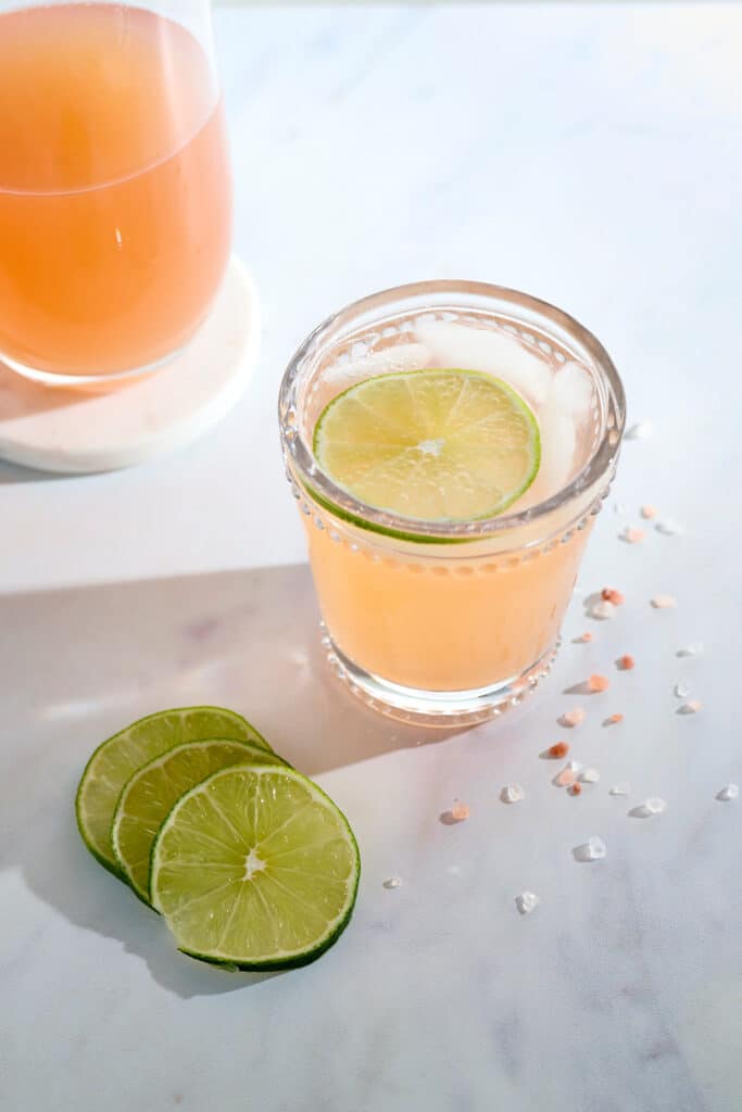 guava cortisol mocktail in a glass with decorative lime slices and salt.