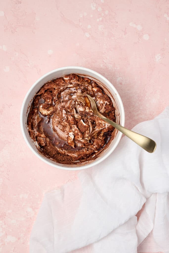 ingredients to make a healthy brownie batter dip in a white bowl with spoon.