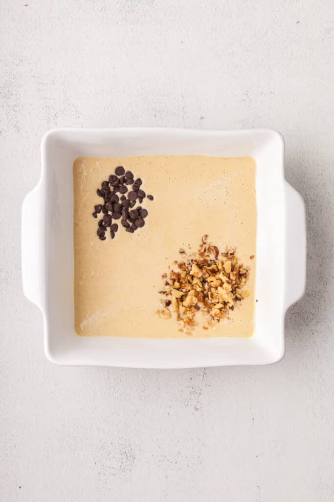 baked oats batter with chocolate chips and walnuts in a baking dish.
