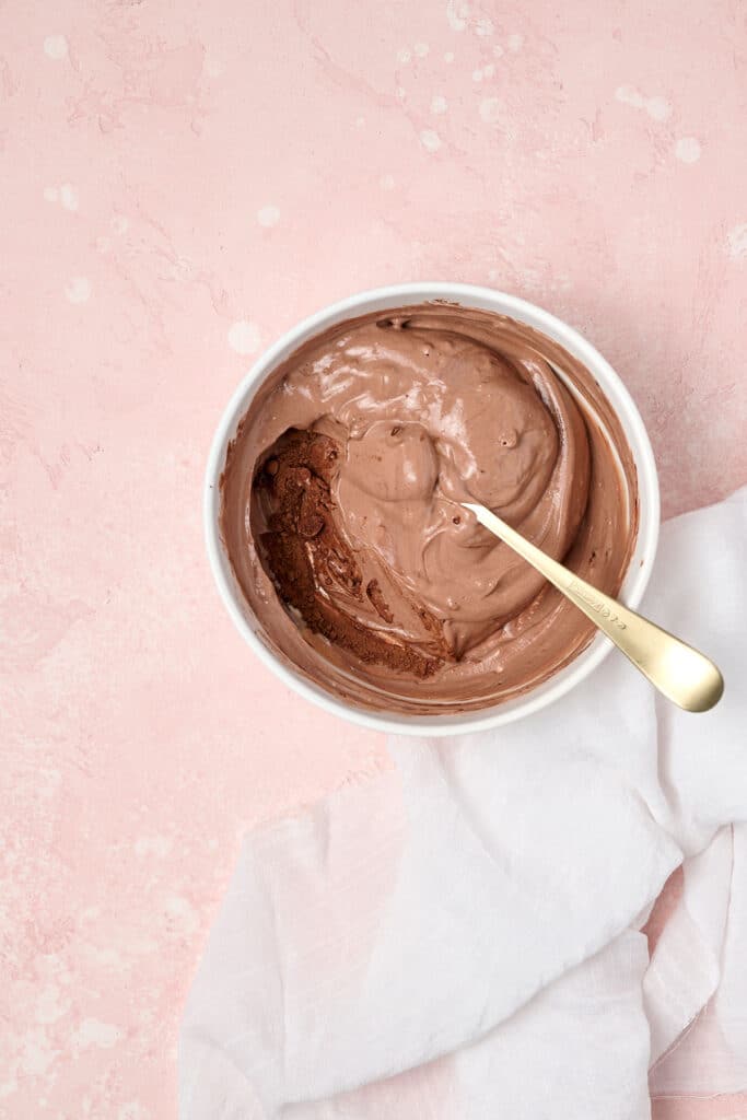 mixing a brownie batter dip in white bowl with spoon.