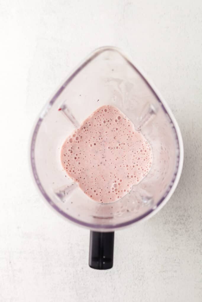 pink smoothie in a blender after being blended.
