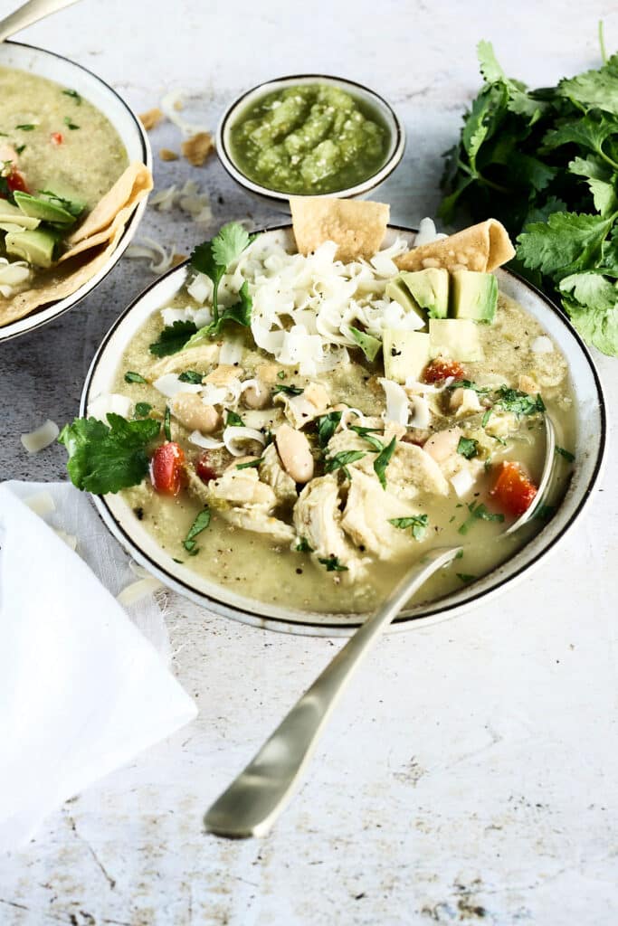 green enchilada chicken soup in a bowl with spoon and toppings.