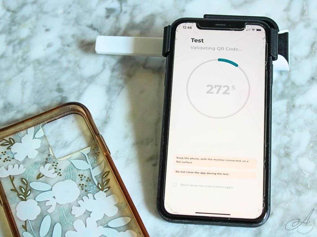 iphone case and iphone with inito monitor attached and test strip inserted sitting on a countertop.