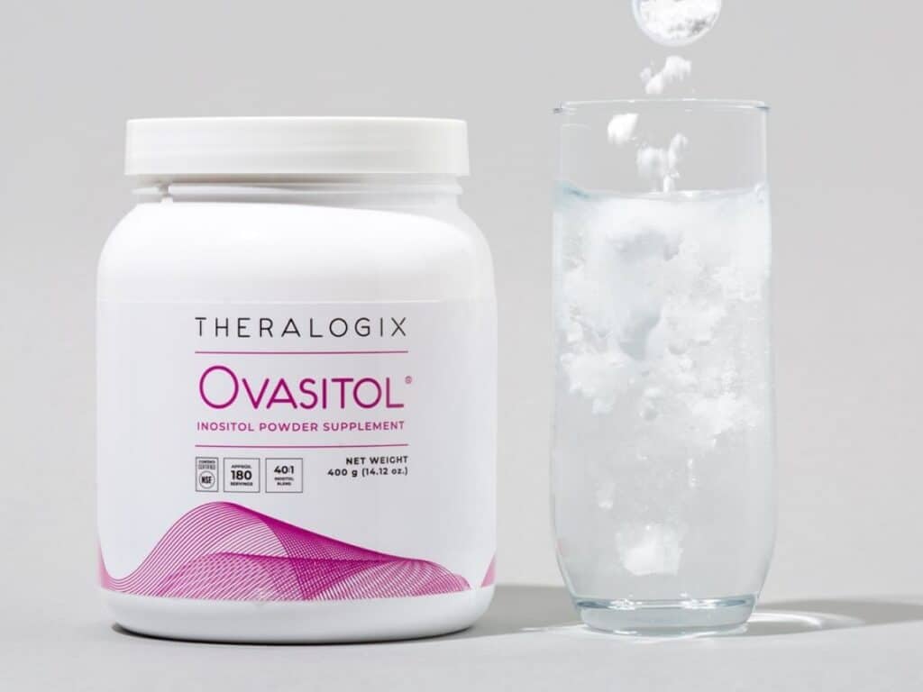 ovasitol canister next to a glass of water with white powder being poured in.