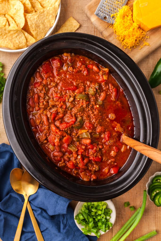 pcos chili in a slow cooker with ingredients surrounding it.