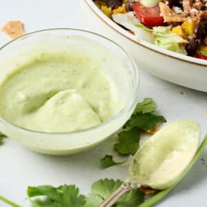 avocado cilantro lime dressing in a small bowl with a spoon next to it.