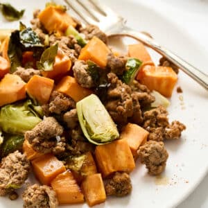 turkey sweet poato hash on a white plate with a fork.