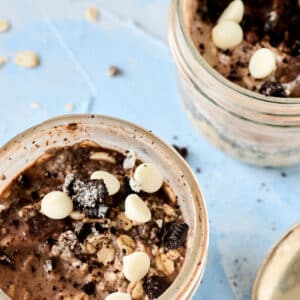 closeup shot of cookies and cream overnight oats in a mason jar with gold spoon next to it.