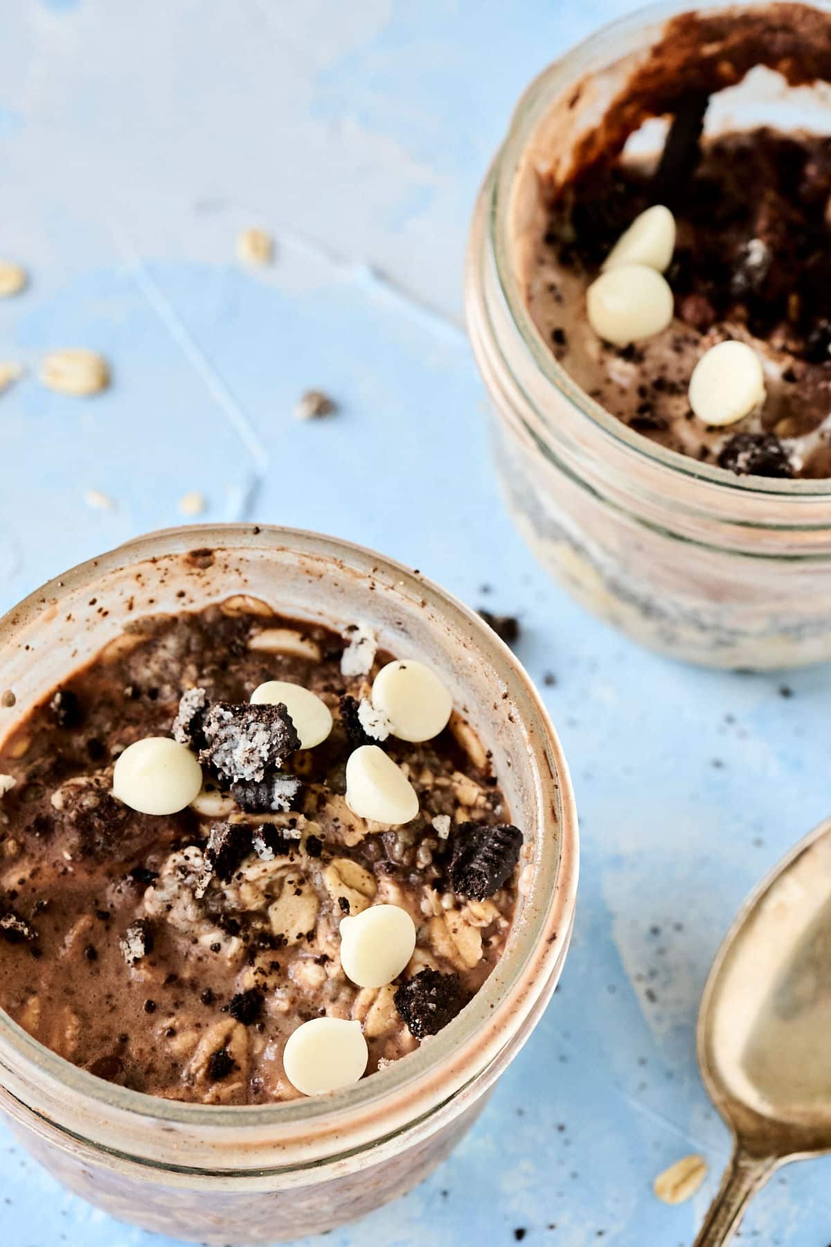closeup shot of cookies and cream overnight oats in a mason jar with gold spoon next to it.