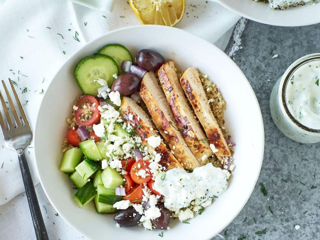greek chicken quinoa bowl with feta cheese in a white bowl.