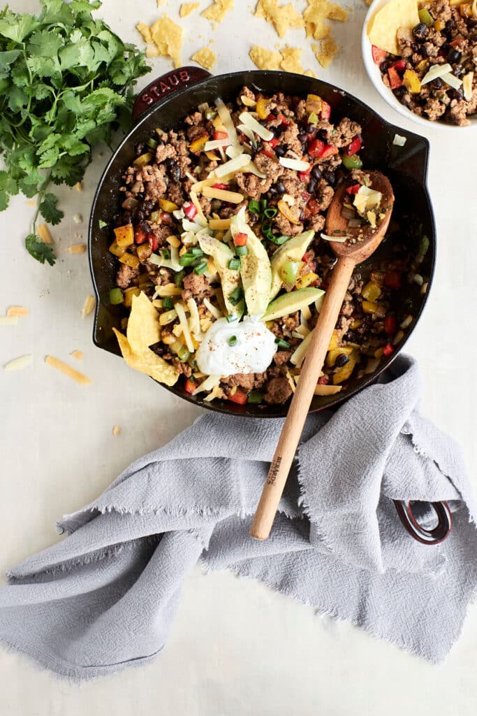 overhead view of ground turkey taco skillet recipe with sliced avocado and a dollop of sour cream.