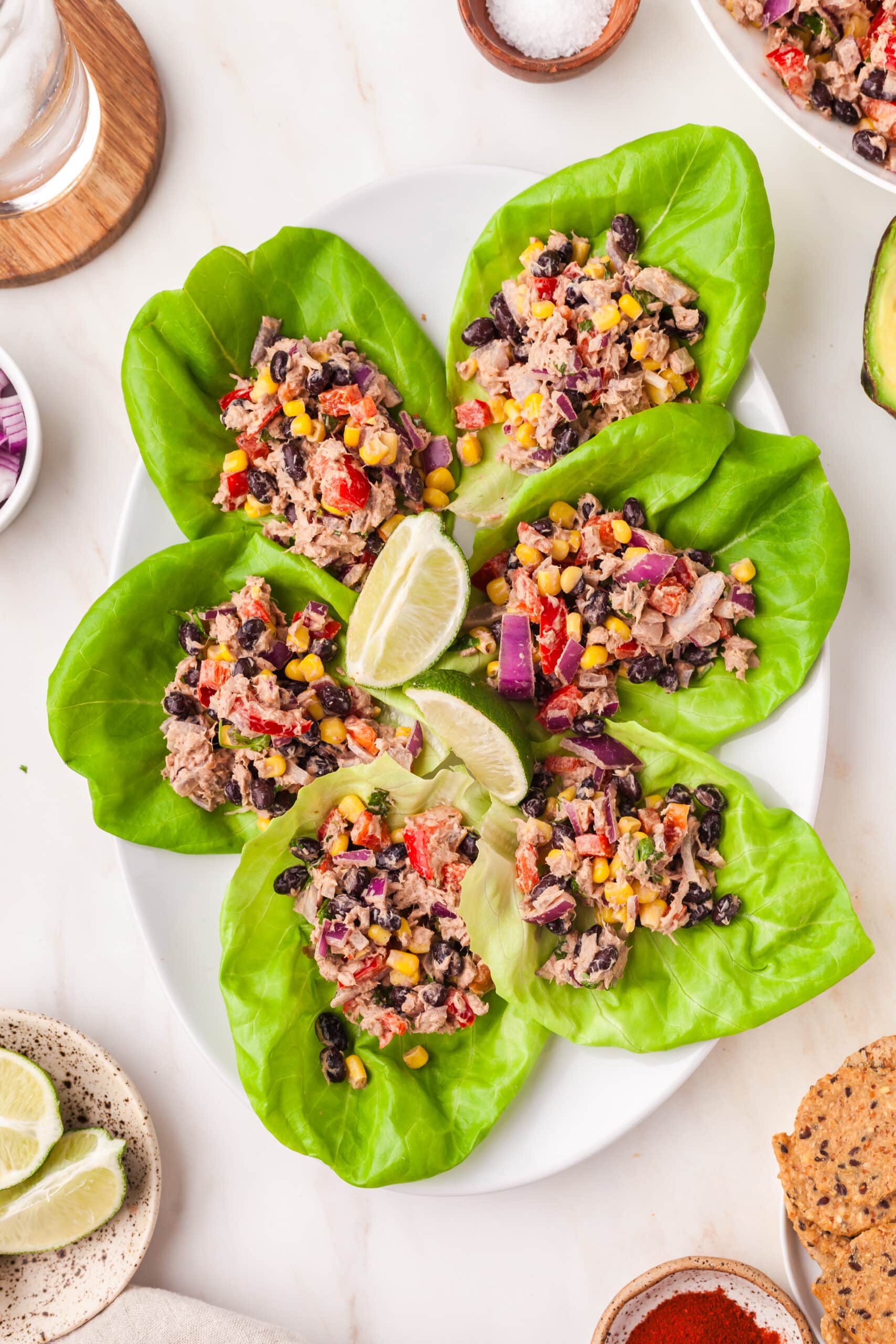 mexican tuna salad scooped onto lettuce wraps on a plate with lime wedges decorative.