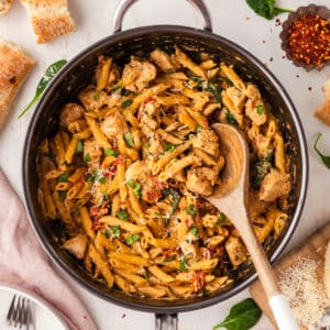 marry me chicken pasta in a skillet with wooden spoon.