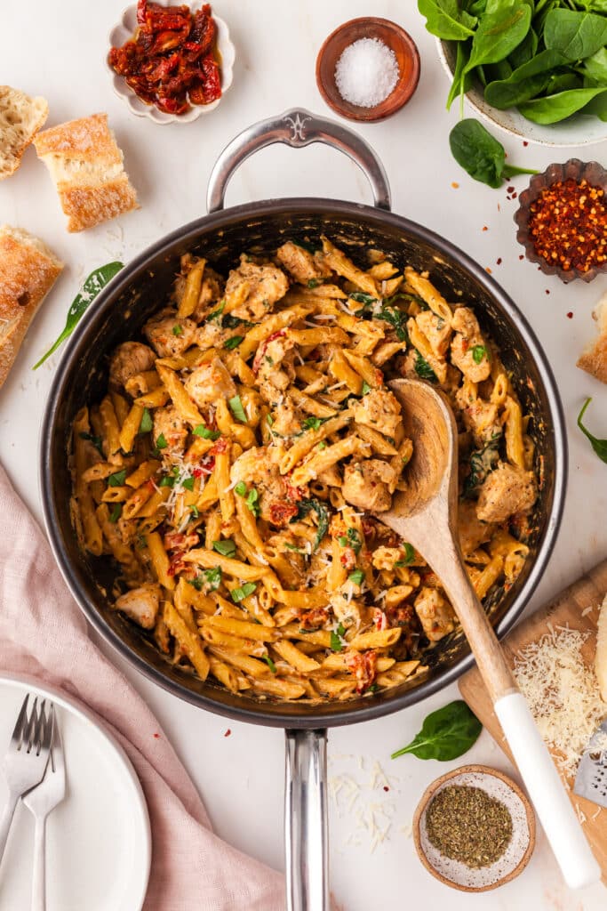 marry me chicken pasta in a skillet with wooden spoon.