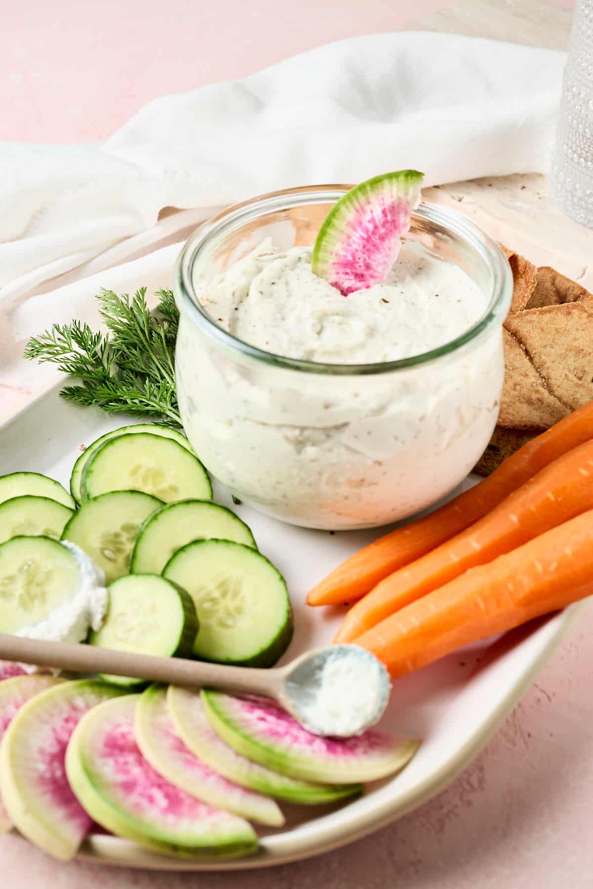 high protein dip with watermelon radish slice in it and fresh veggies surrounding on a platter.
