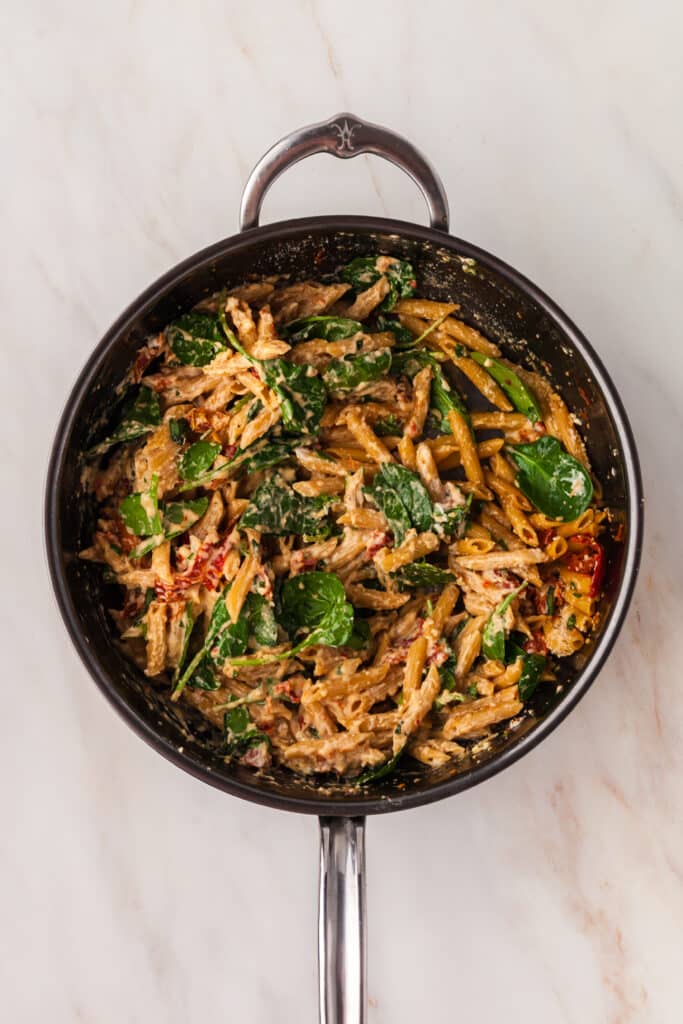sun-dried tomatoes, spinach, and pasta in a skillet.