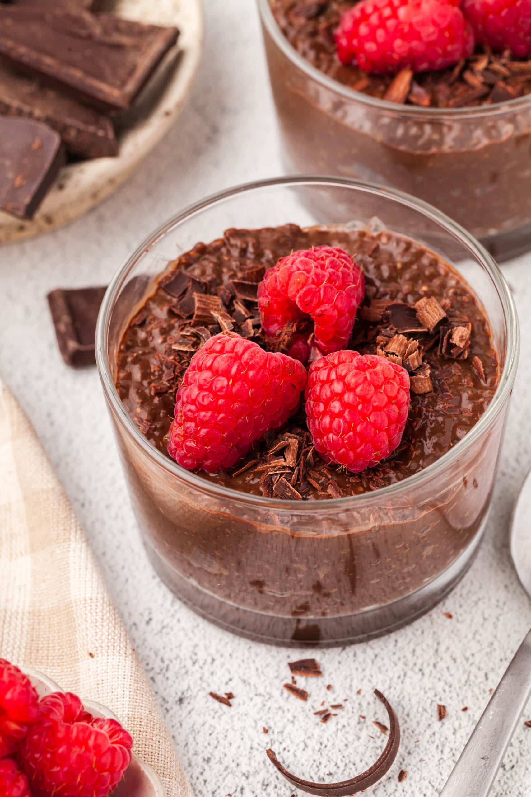 chocolate chia pudding recipe in a glass jar with raspberries on top.