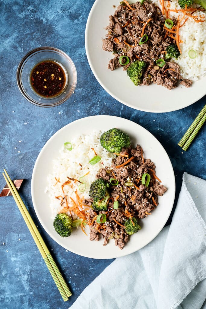 korean ground beef bulgogi with white rice and veggies on a white plate; chopsticks next to it.