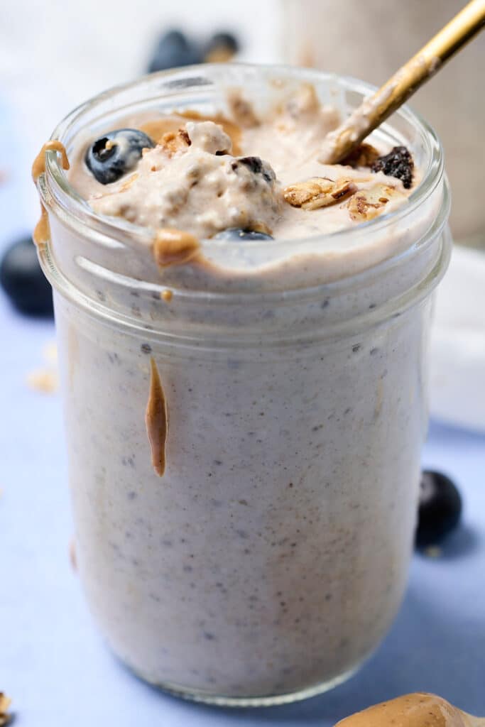 blended overnight oats in a mason jar with blueberries and nut butter mixed in.