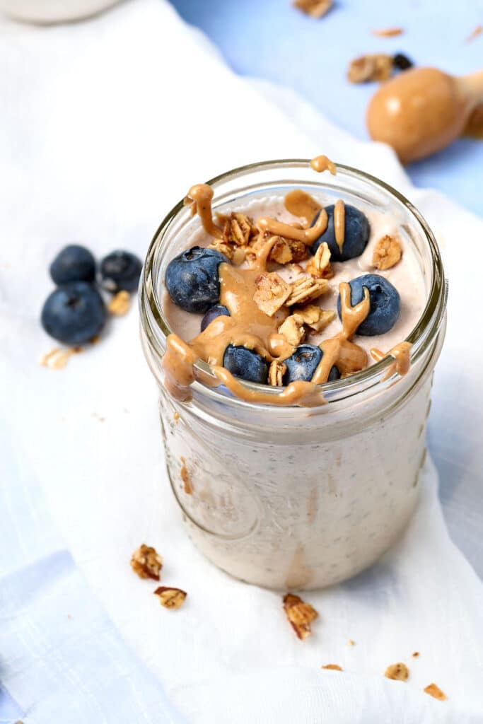 blended overnight oats in a mason jar with blueberries and nut butter drizzle.