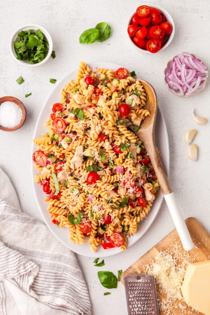high protein pasta salad on a large white plate with wooden serving utensil.