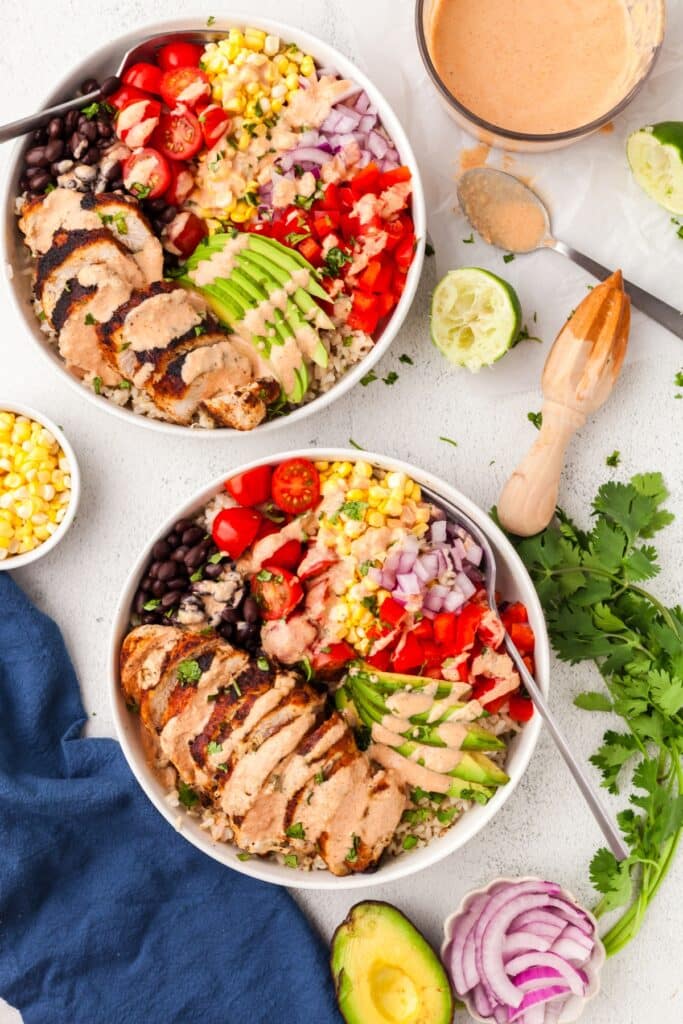 southwest chicken bowls on a countertop surrounded by ingredients.